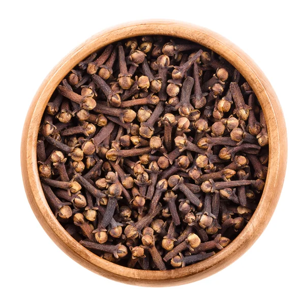 Dried cloves in a wooden bowl over white — Stock Photo, Image