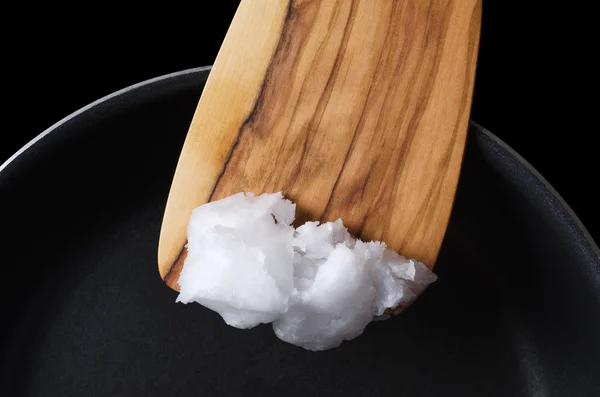Кокосова олія на дерев'яній шпателі над тефлоновою сковородою — стокове фото