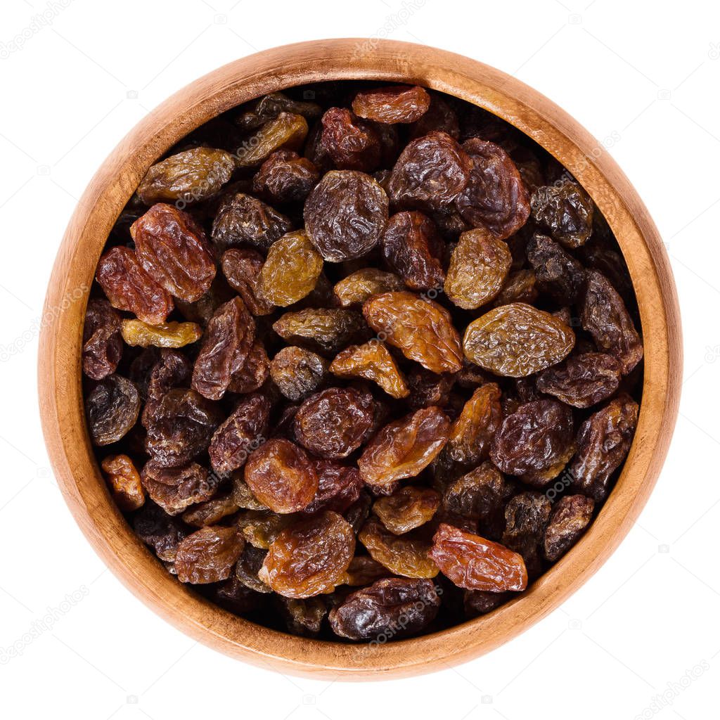 Dark brown raisins in wooden bowl over white