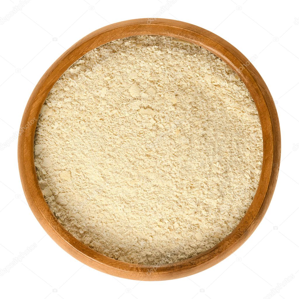 Nutritional yeast flakes in wooden bowl over white