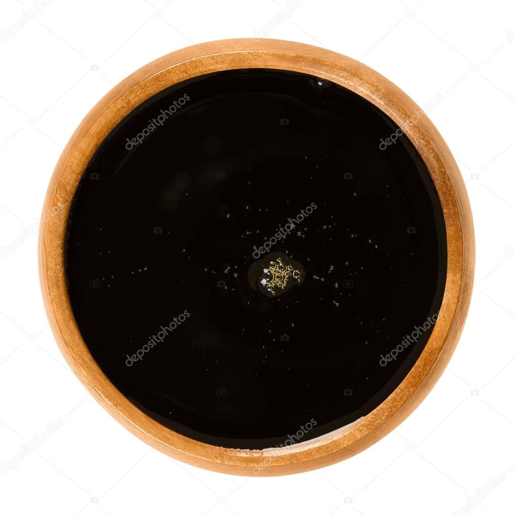 Apple juice concentrate in wooden bowl over white
