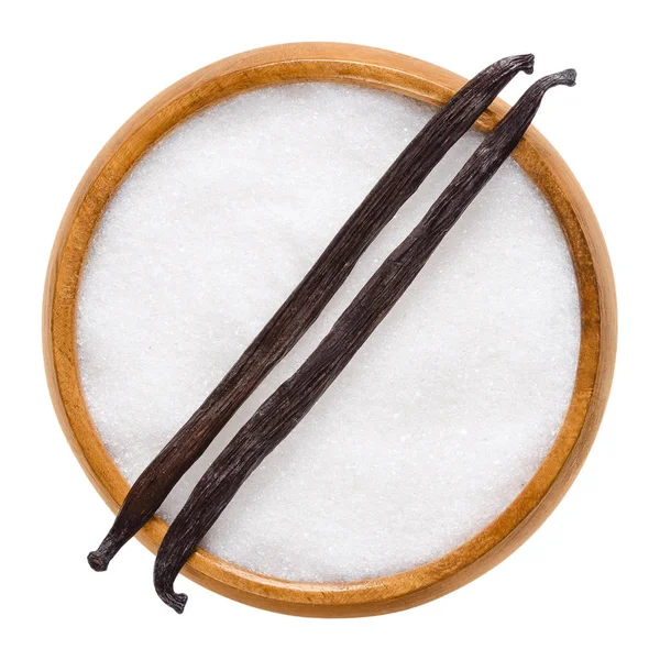 Две сушеные ванильные стручки Бурбона поверх сахара в деревянной миске — стоковое фото