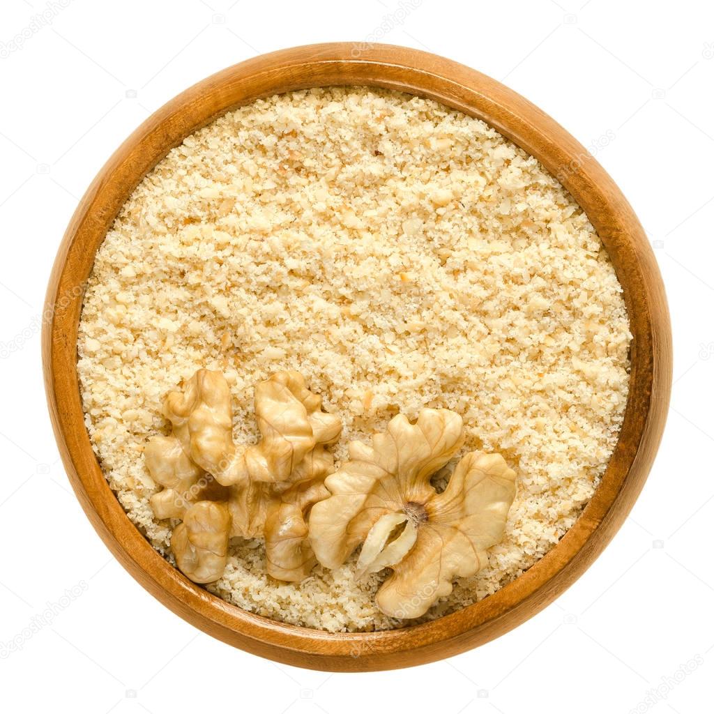 Ground walnuts and walnut kernel halves in wooden bowl