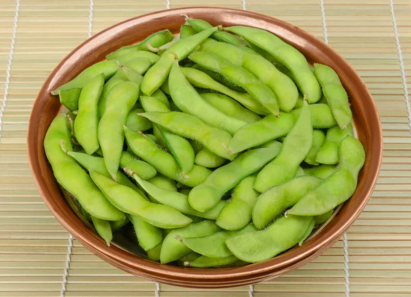 Boiled edamame, green soybeans in bowl on bamboo mat — Stock Photo, Image