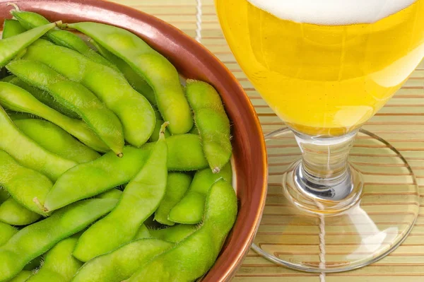 Gotowany edamame w brązowej misce ze szklanką piwa — Zdjęcie stockowe