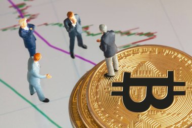 Makro minyatür işadamı figürü altın bitcoin yığınının üzerinde duruyor ve diğer iş adamlarıyla konuşuyor. Arkaplanda borsa grafikleri var. Geleceğin para birimi ve engel zinciri konseptiyle ilgili iş toplantısı.