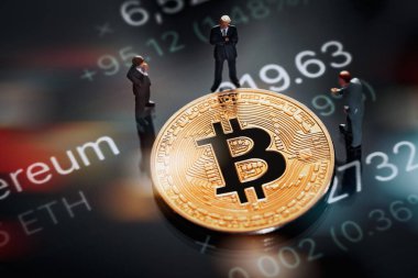 Bitcoin konsepti için yatırım kararı hakkındaki iş toplantısı: Parlak altın bitcoin 'in yanında duran Macro minyatür işadamı figürleri. Borsa fiyatları ve arka plandaki değerler. 