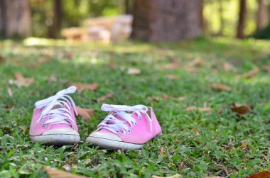 Yeşil çimenlerin üzerinde pembe spor ayakkabıları. Ayakkabı olmadan Park'ta dinlenme.