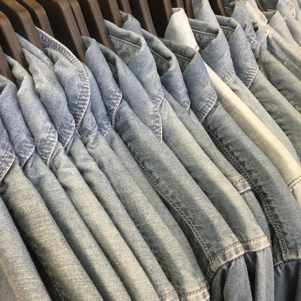 Camisas de ganga penduradas em um rack na loja . — Fotografia de Stock