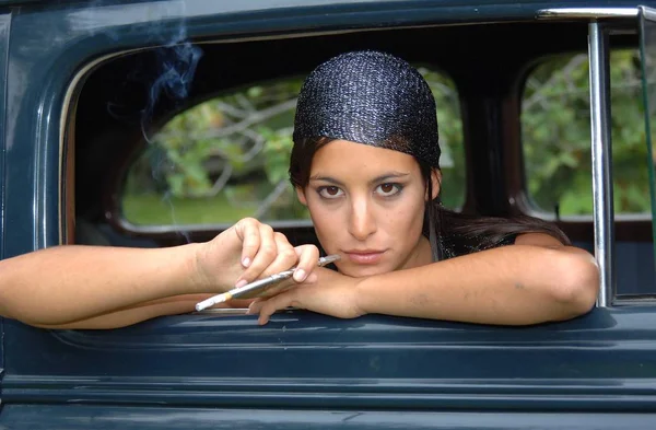 Beautiful woman smoking in an old car — Stock Photo, Image