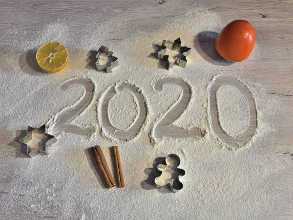 year 2020 written by hand on flour surface with Christmas fruits