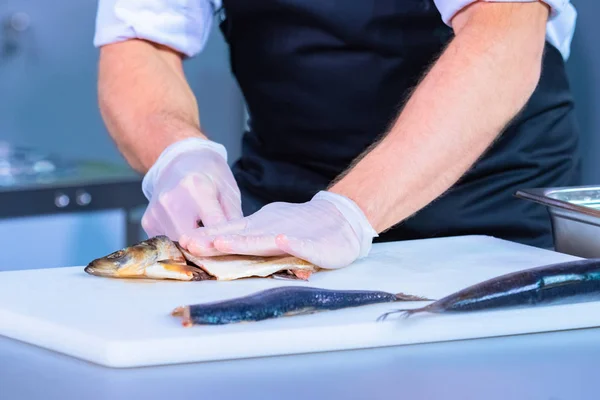 Human is cutting fish. Cooking slave dishes. Cook cuts fil from fish. Cook works in gloves. Seafood. Cook\'s career. Master class from the chef. Cooking filet. Cooking. Work in a restaurant.