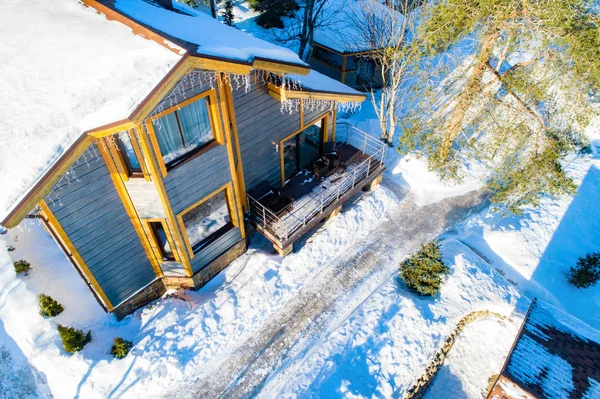 Two-story house top view. Wooden cottage. Frame house in winter weather. Snow drifts near the house. Concept snow removal services. Country real estate. Land plot view from a quadcopter. Fairy lights
