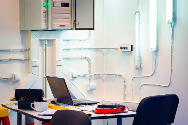 Insulation resistance meter on an electrician\'s desk. Electrician tools near the computer. Insulation tester next to a laptop. Concept - electrician�s office. Utility landings at the enterprise