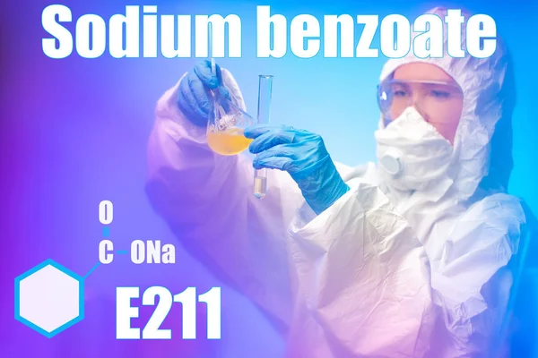 Sodium benzoate. Chemical. Food additive. Preservative. E211. The girl is a chemist holding a test tube and flask with chemical substances. Chemical formula of sodium benzoate.