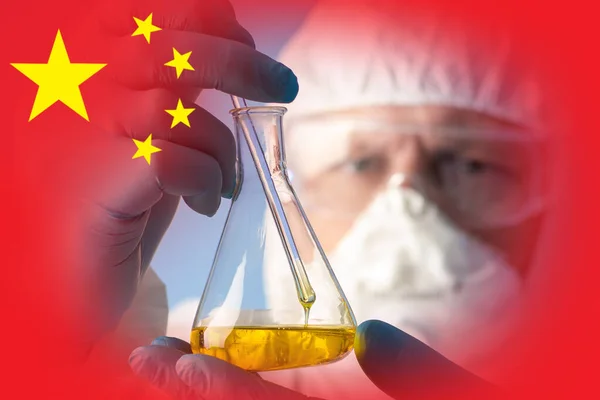 China\'s chemical industry. Development of new synthetic substances in China. A man in a protective suit studies a chemical liquid in a test tube on the background of the flag of the PRC.