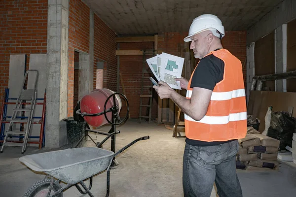 Builder at a construction site. A man with construction drawings
