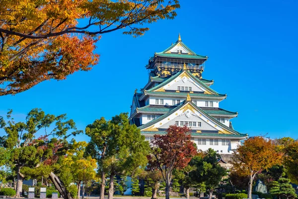 Japan. Osaka. A multi-storey samurai castle in Osaka. Autumn in Osaka. Castle on the background of autumn trees and blue sky. Sights Of Japan. Guide to East Asia. Architecture Of Japan.