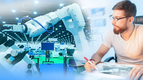 Testing an industrial robot. The engineer monitors the operation of the programmable robot and records the results. Production automation. Robotics. Use of robots in production.