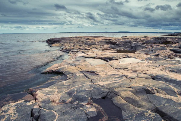 Russia. Karelia. Ladoga Lake. Rocks on the coast. The stone shore of Lake Ladoga. Water. Northern nature. The coast of Karelian lake. Guide to Russia. Tourism in the Russian Federation.