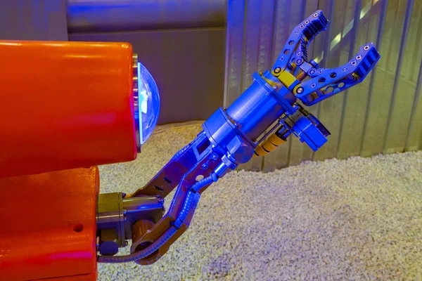 Robot arm. Robotic equipment. Droid looks at his hand. Mechanism Blue chela of a robot. Robotics Modern technologies. futuristic car. Red robot close-up. Concept - small robots. Eye.