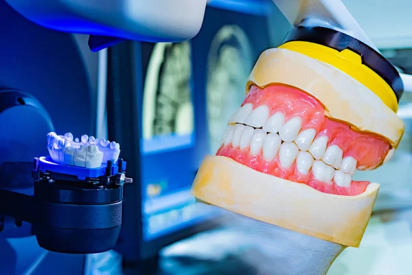 Milling dental system with computer control on the background of the layout of the jaw. Dental concept. Workplace of a dental technician. Grinding and milling machine for dentures.