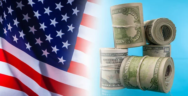 Illegal earnings in the United States. Cash payments in America. Concept of illegal funds. Hundred-dollar bills are twisted and connected with elastic bands on the background of the American flag.