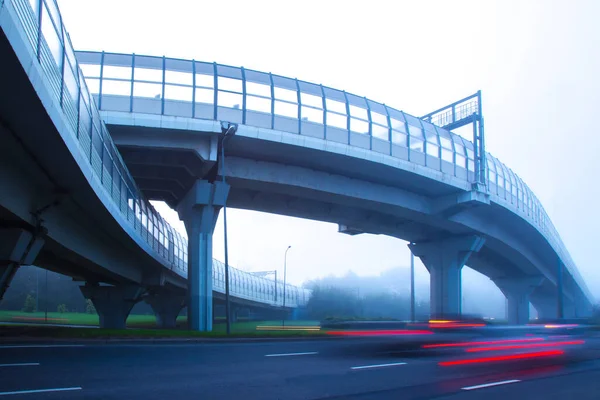 High-speed roads with protective screens. Movement of cars in the fog. High-speed auto movement in different directions. Organization of traffic. Road infrastructure. Road junction.