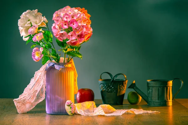 Still life of flowers, apples and dishes. Bouquet of hydrangea, lysianthus and white peony on the table. Romantic still life. The composition of flowers, apples and lace is illuminated by the sun.