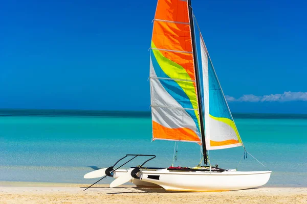 Boat with a sail on the Caribbean sea. Vacation in Cuba. Sailboat on a background of white sand and emerald water. Water sport. travel to Cuba. A sailboat ride. Vacation in the Caribbean.