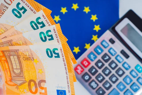EU flag, calculator and Euro. Financial policy of the EU countries. Dynamics of the Euro exchange rate. Income of citizens of European countries. Tax policy in EU countries.