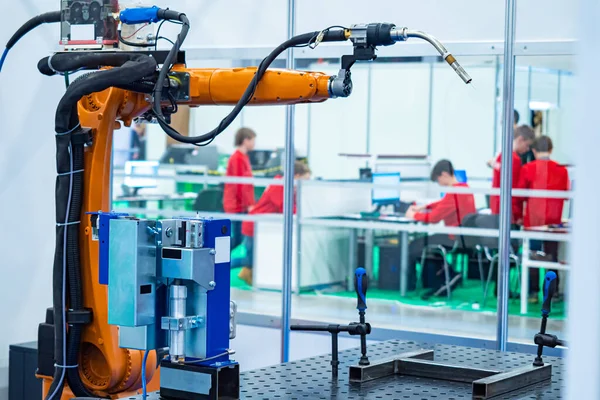 Robotics. Robotic arm on the background of a robotics training class. Computer programming of robots. Creation of algorithms for robot actions. Teenagers learn to create computer programs.