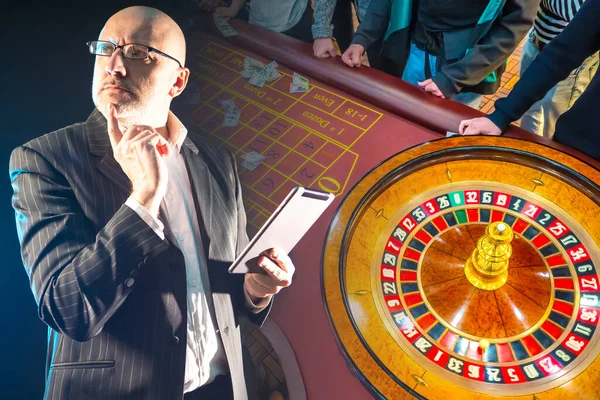 Virtual game. A man is going to play in an online casino. A man with a tablet on the background of roulette. Gambling for money. Betting in online casinos.