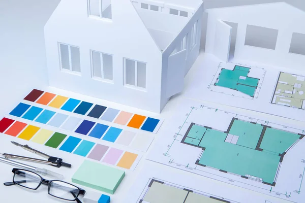 Development of the concept of a new home. Building plans, color palette and layout of the cottage on a white table. Workplace construction designer. Architectural and construction Bureau.