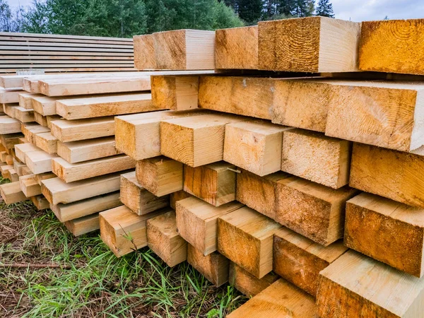 Wooden beams of different sizes. Lumber. Concept - sale of wood for construction. Piles of wooden beams lie on the ground. Concept - Buying wooden slings for building a house. Open-air lumber