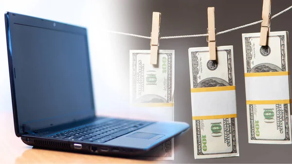 A laptop next to money on a string. Dollars are dried on a rope. Concept - money laundering via the Internet. Illegal computer business. Offshore. Concept - illegal internet business.