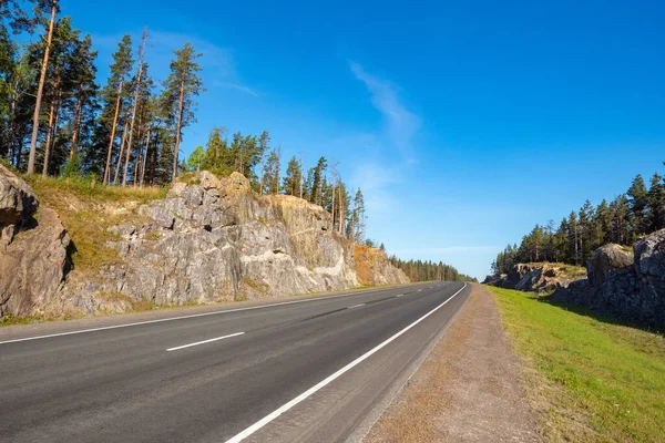 Road in Karelia. Russia. Highway in the Russian forest. Traveling by car in Russia. Road in rocky terrain. Highway away from the city. Journey through Corellia. Nature of the Russian Federation.