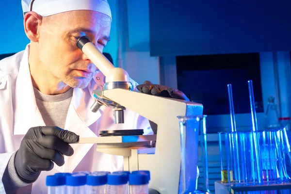 The chemist examines the substance with a microscope. Studying a sample of material under a microscope. Research in the field of medicine. Smear microscopy.