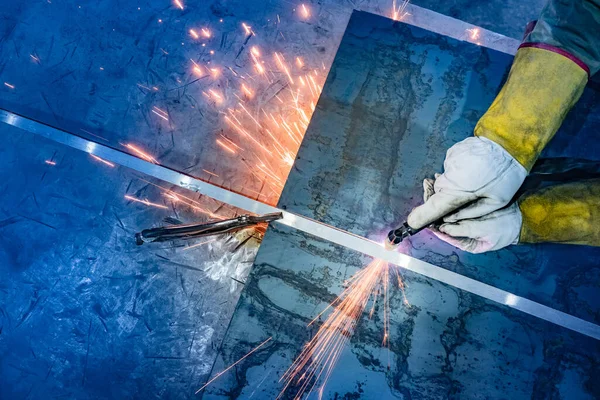 A worker cuts a sheet of metal with a plasma metal cutter. Plasma cutting of metal. Equipment for Metalworking. Work at a Metalworking company.