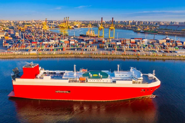 Red container ship on the fairway. Sea commercial port. Transportation of goods by water. Merchant fleet. Colorful containers are waiting for loading. Loading and unloading in the port.