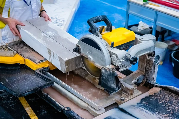 Circular saw in production. Sawing a concrete slab. Cut a stone plate with a circular saw. Stationary circular saw. Mason. Stone processing. Stone production. Build. Work on a construction site.