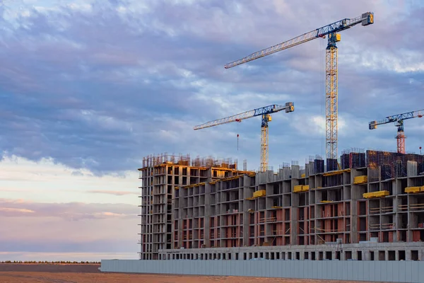 Construction of a multi-storey building. Apartments in new buildings. Construction site without workers. Advertising for a construction company. Future home and cranes against the sky.