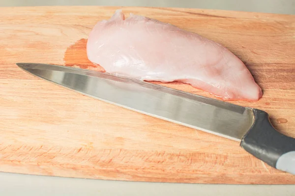 Сырое филе куриной грудки с ножом на деревянной доске . — стоковое фото