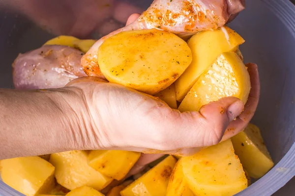 Женская рука маринует куриные ножки с картошкой для выпечки в духовке . — стоковое фото