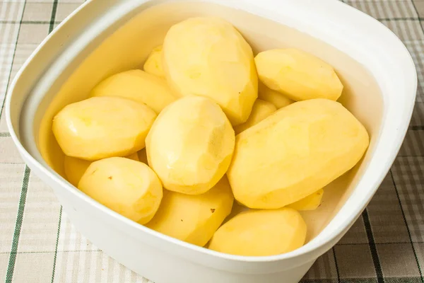 Cleaned potatoes lie in water from blackening of nitrates. — Stock Photo, Image