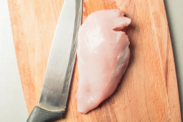 Raw chicken breast fillet with cutting knife on wooden board. — Stock Photo, Image