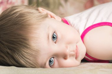 Büyük mavi gözlü sıkıcı çocuk kanepede yatıyor.