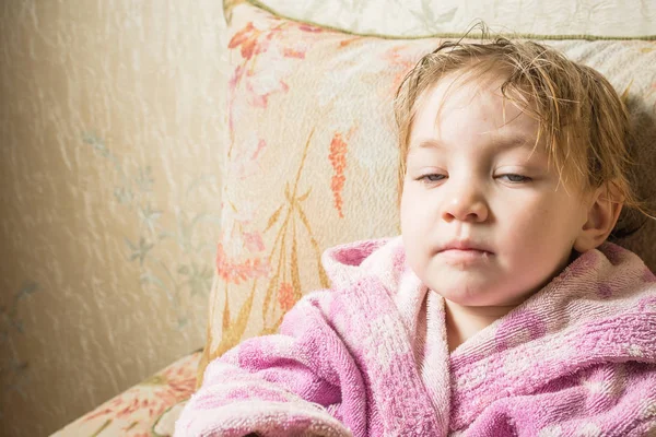 Bébé mignon avec cheveux mouillés après le bain dans le peignoir sèche sur le canapé . — Photo