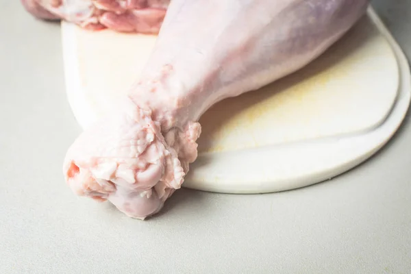 Pernas de peru cruas descongeladas na placa de corte branca para cozinhar . — Fotografia de Stock