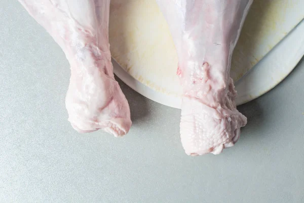 Patas de pavo descongeladas en tabla de cortar blanca para cocinar . — Foto de Stock